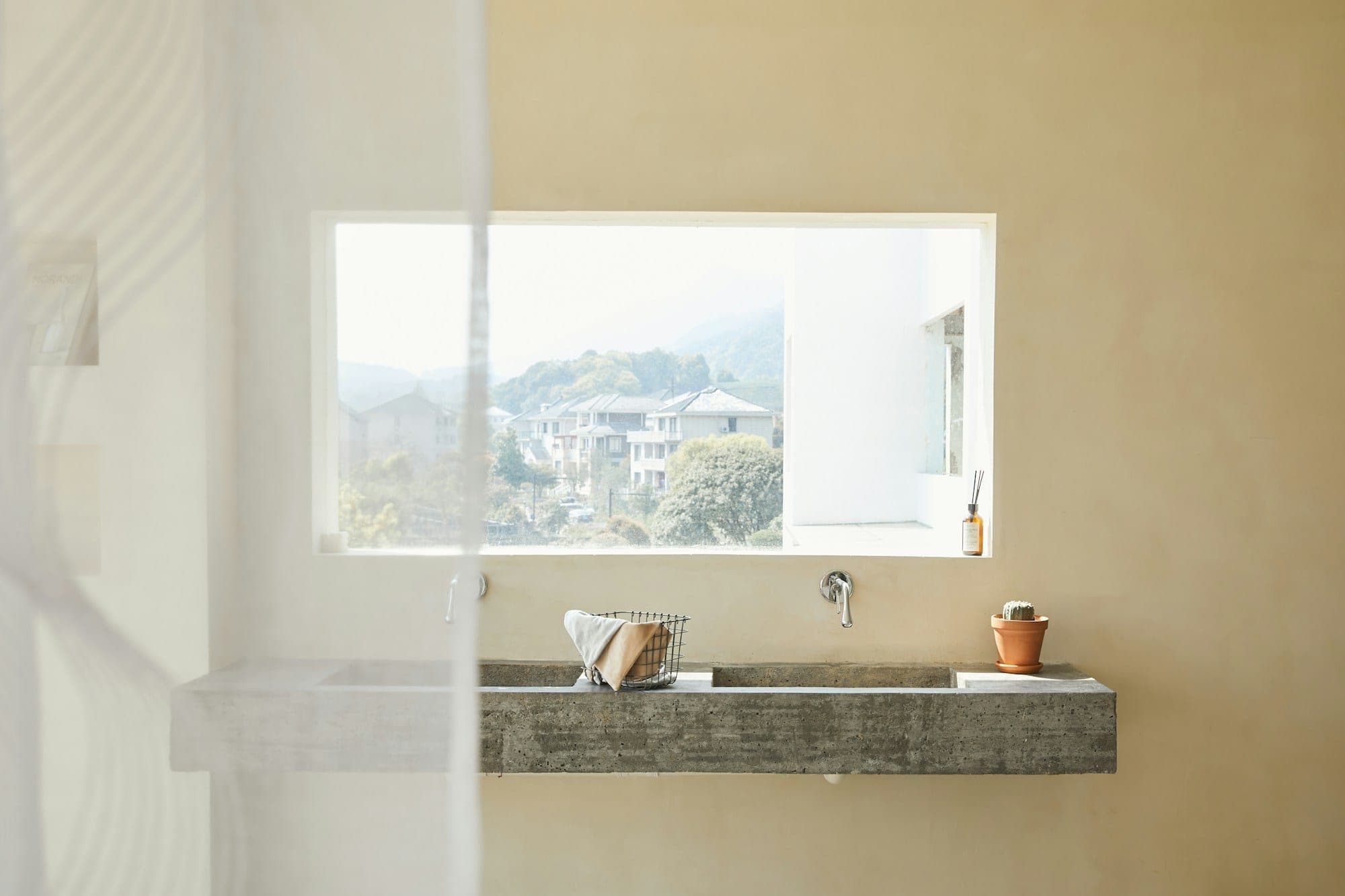 Bagno luminoso con doppio lavabo sospeso, ampia finestra e pareti continue chiare