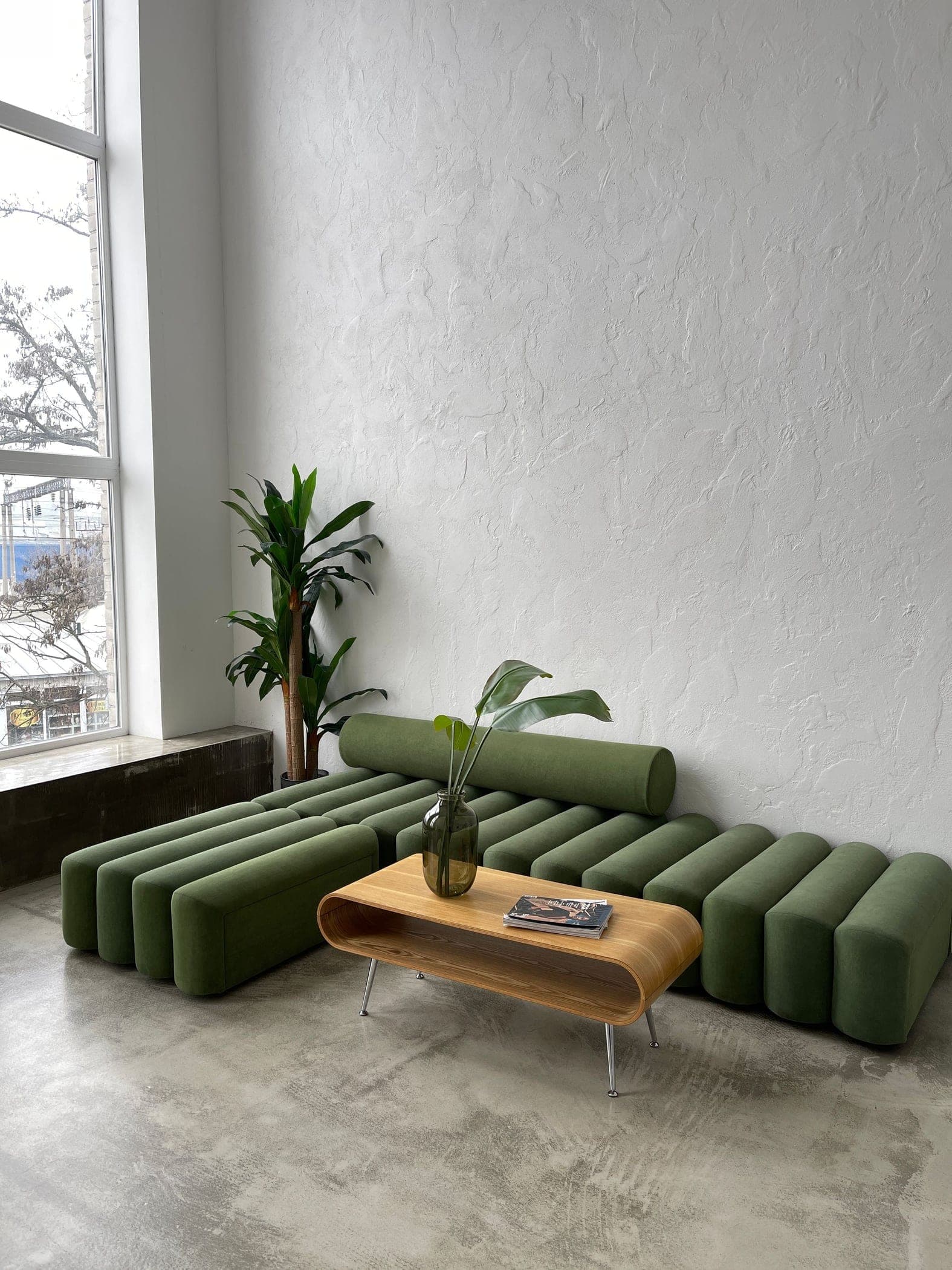 Living luminoso con superficie continua grigia, parete materica e arredo contemporaneo