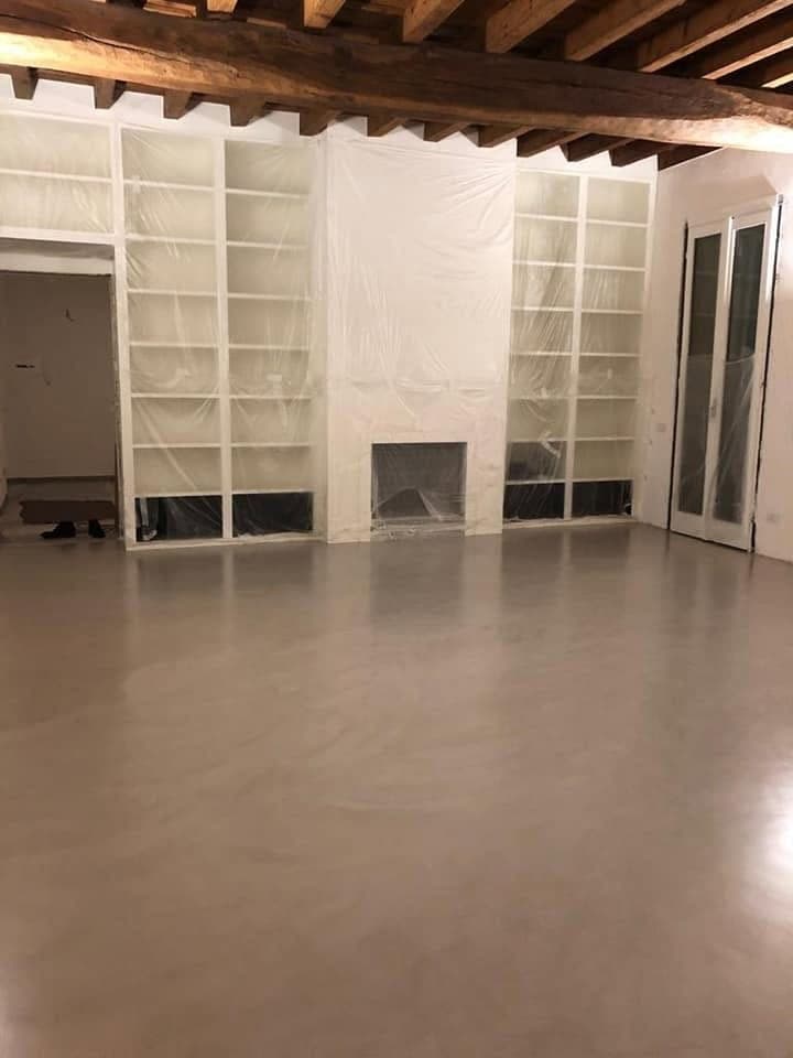 Ambiente con pavimento continuo caldo e scaffalature chiare
