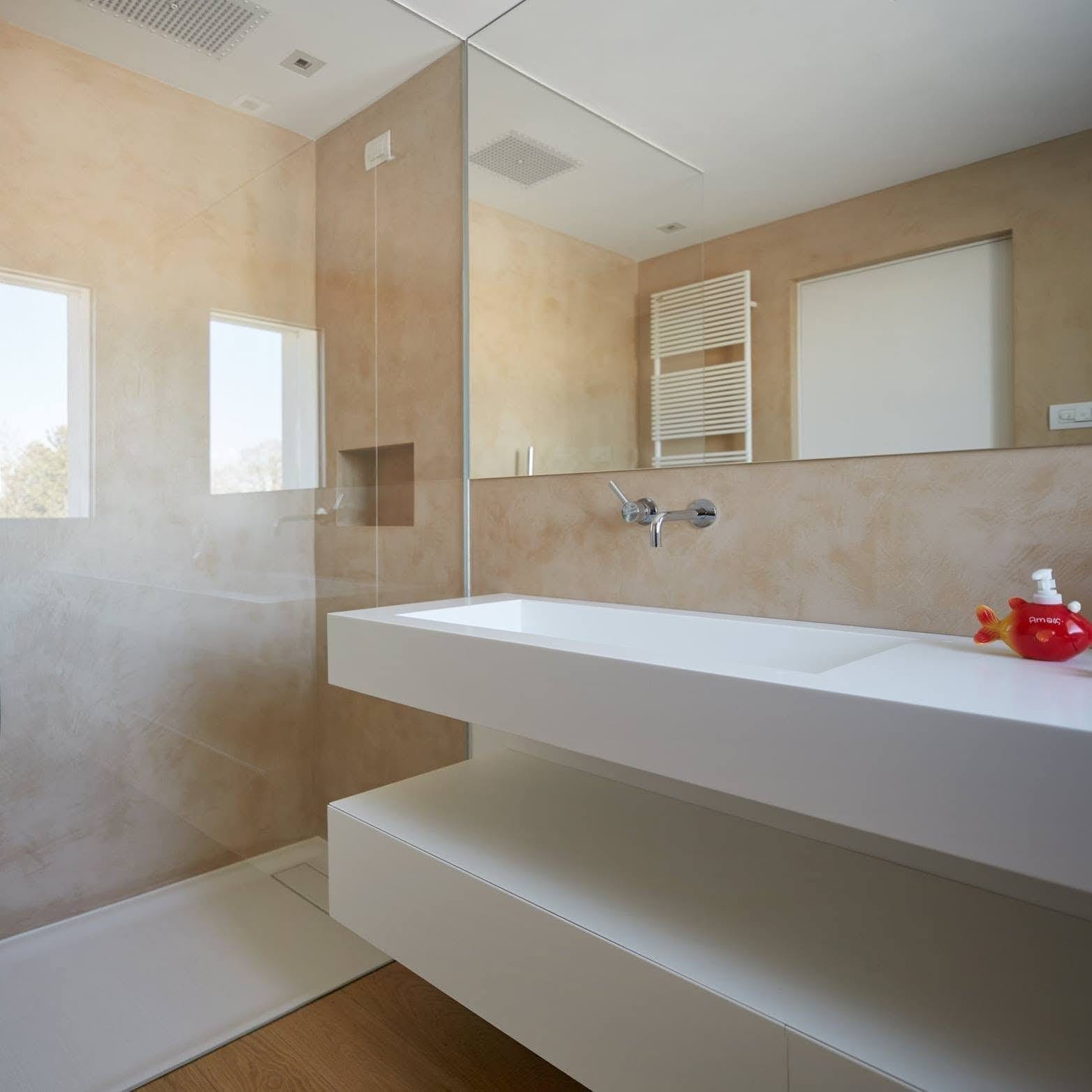 Bagno con pareti continue in tonalità sabbia, doccia e lavabo sospeso