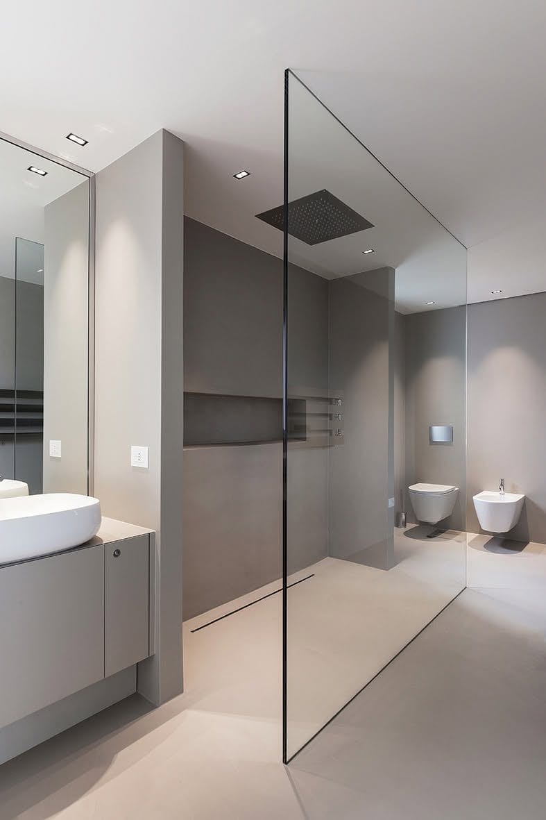 Bagno contemporaneo con doccia vetrata e superfici continue grigie